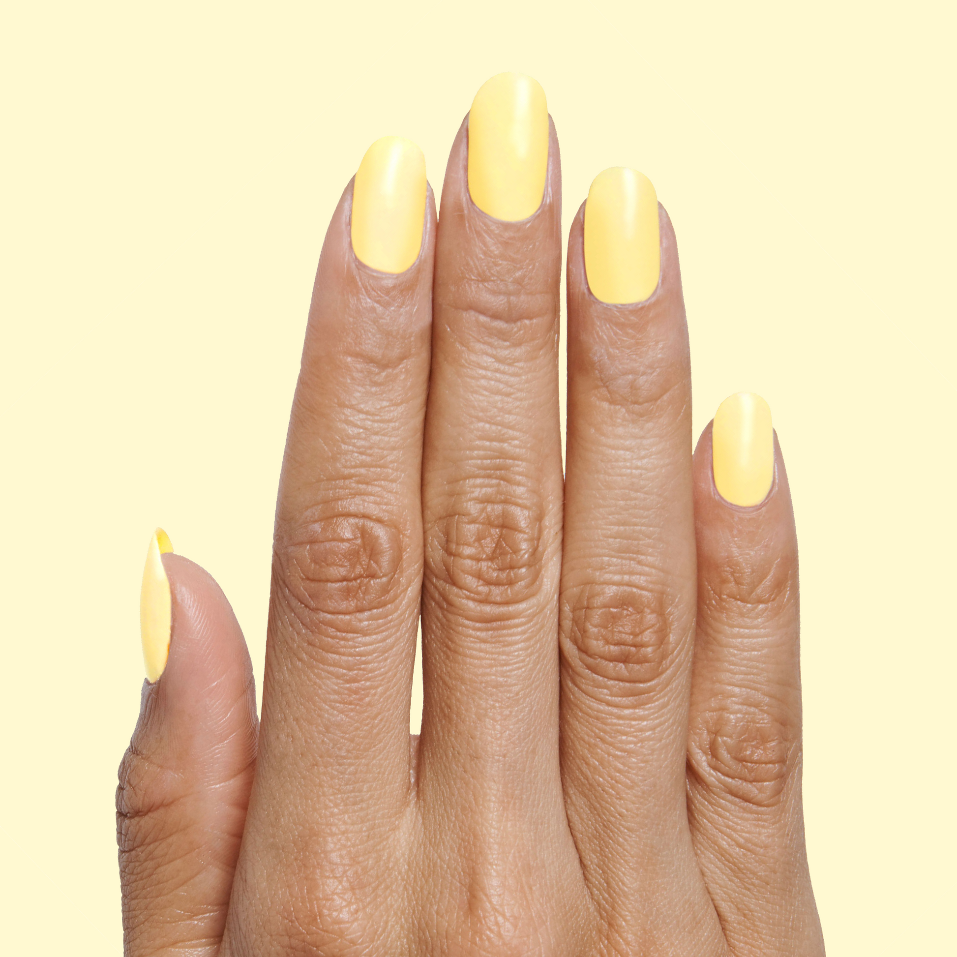 Hand with nails painted in Bright & Focused yellow for a bright, creative at-home manicure look using gel polish