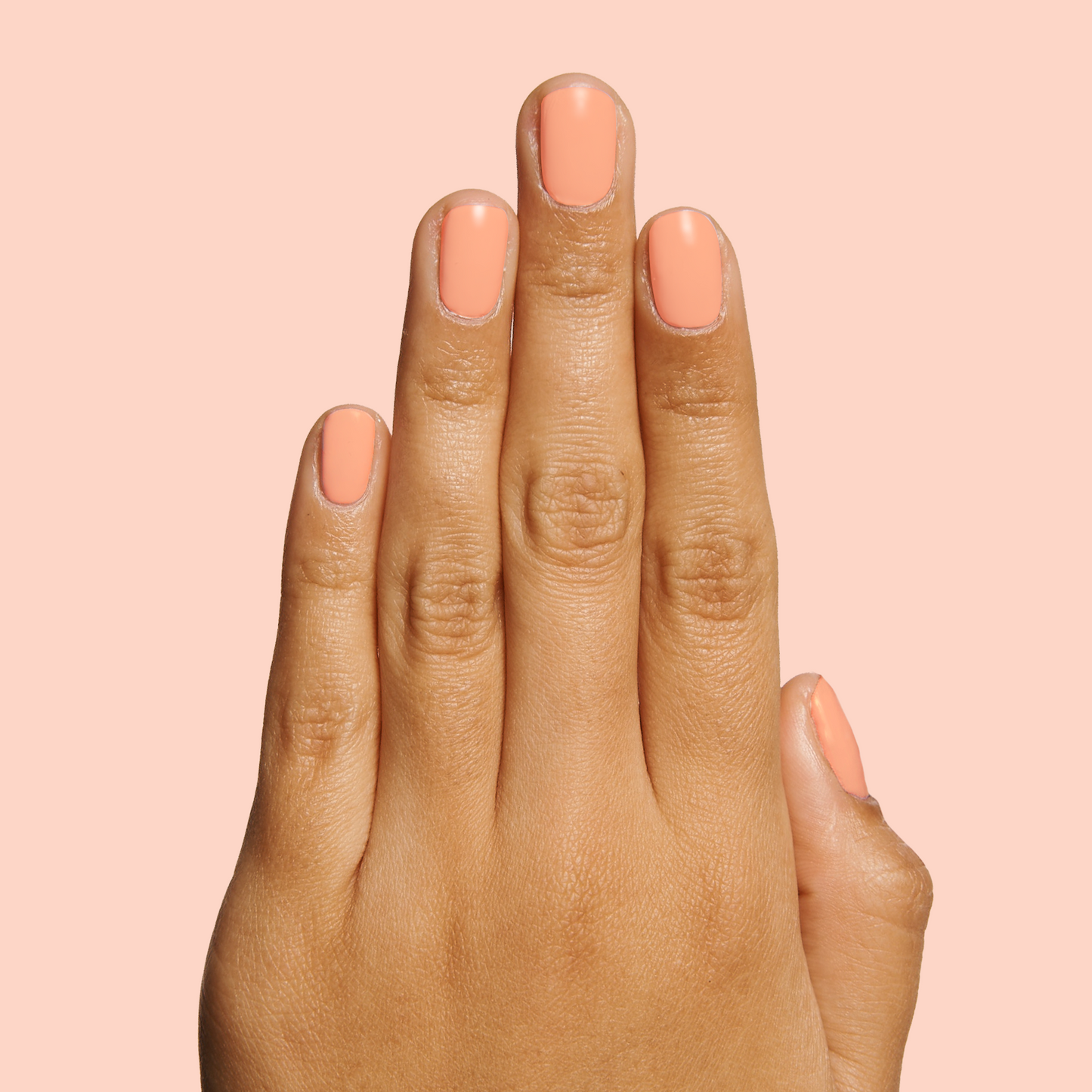 Hand with nails painted in soft coral shade Wild & Free for a vibrant and quick dry at-home manicure