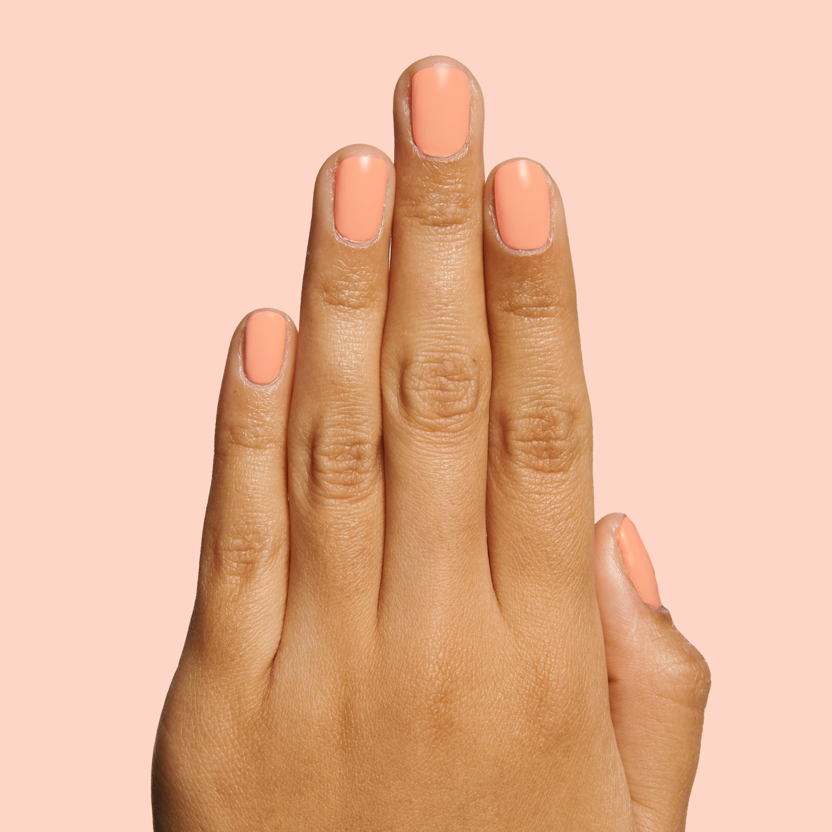 Hand with nails painted in soft coral shade Wild & Free for a vibrant and quick dry at-home manicure