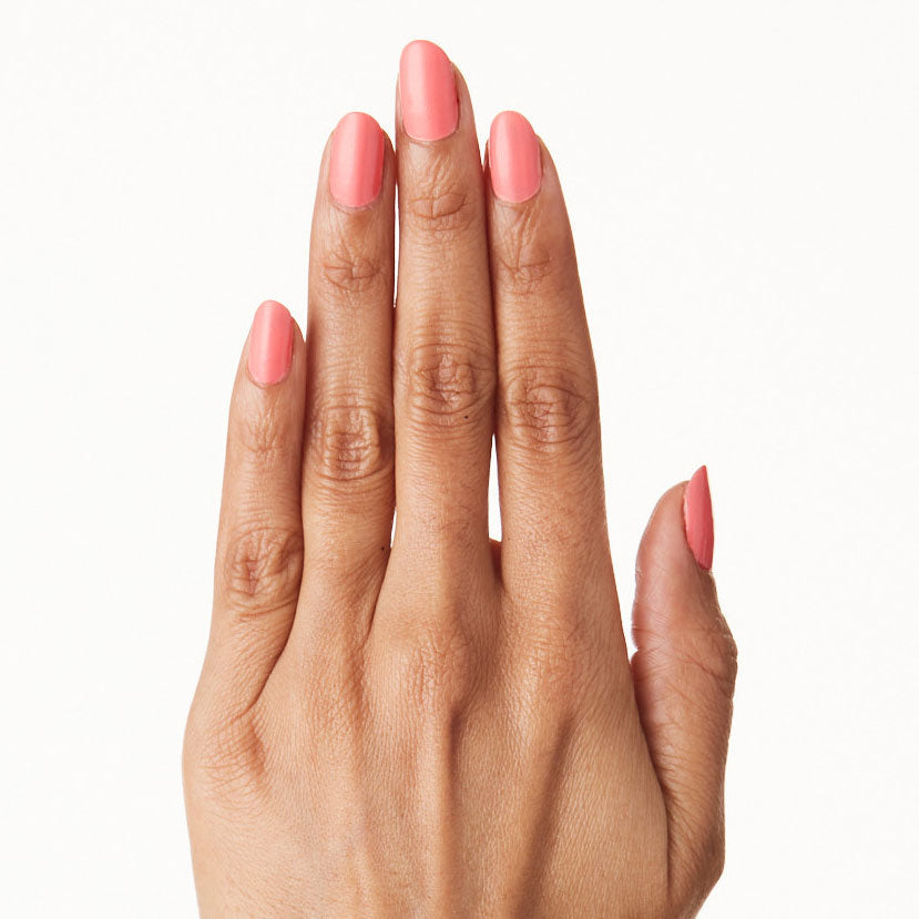 Hand with nails polished in Stinson Sunset gel polish by Olive and June showing a peachy-pink manicure