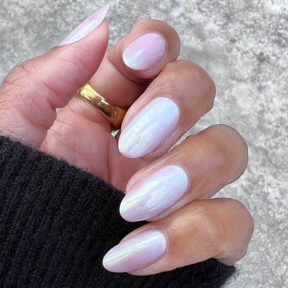 Hand with oval nails coated in Purple Puka gel polish showing a soft milky lavender iridescent manicure