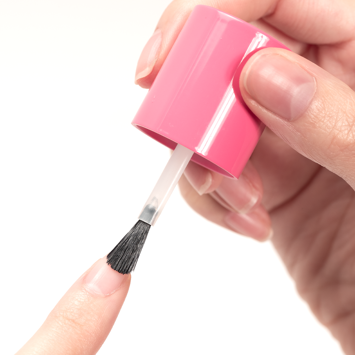 Hand applying Advanced Nail Strengthener with brush to natural fingernail for durable nail growth and protection.