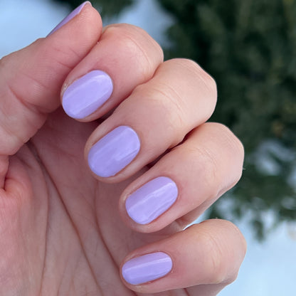Hand with nails painted in glossy lilac shade of You're Invited gel polish for smooth, long-lasting manicure by Olive and June