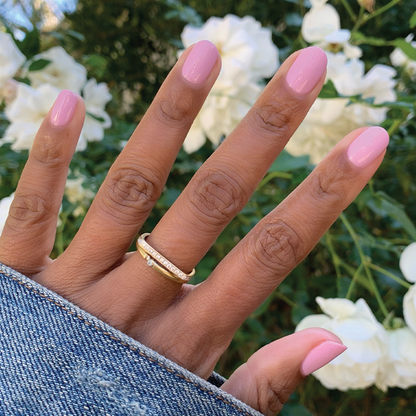 Hand with nails painted in glossy Cockatoo polish by Olive and June showing a soft glowy lavender manicure outdoors