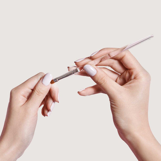Hands holding the Clean Up Brush tool designed for precise polish removal and clean manicure edges at home