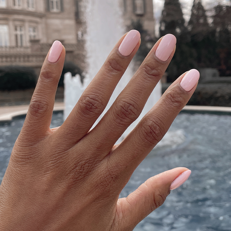 Hand with nails coated in GH, an opaque baby pink polish for a fresh and versatile at-home manicure look