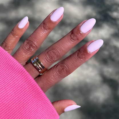 Hand with long almond nails painted in Gelato gel polish showing a soft baby pink manicure outdoors