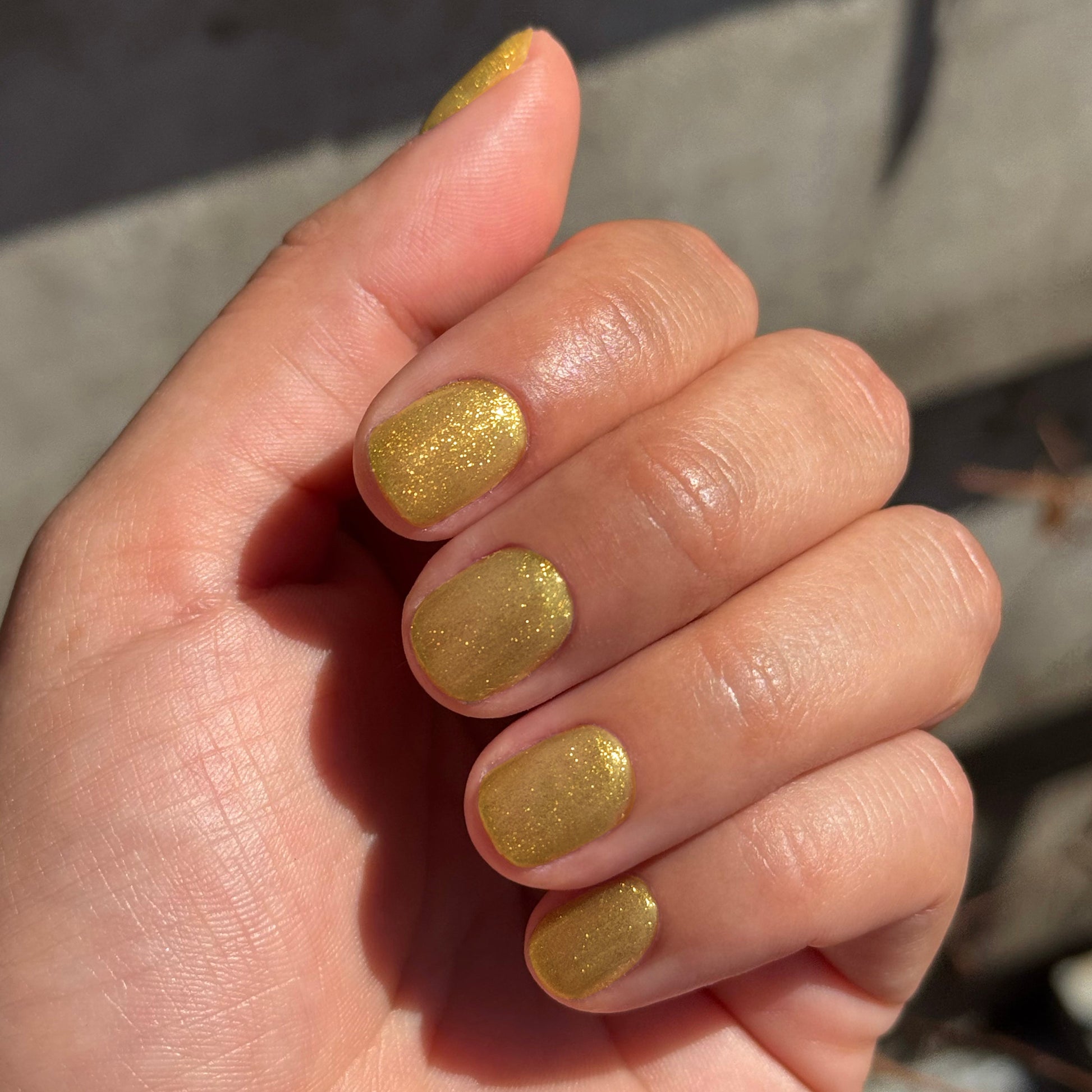 Hand with nails painted in Golden Velvet - Gel showing sparkling golden bronze manicure with magnetic gel polish effect
