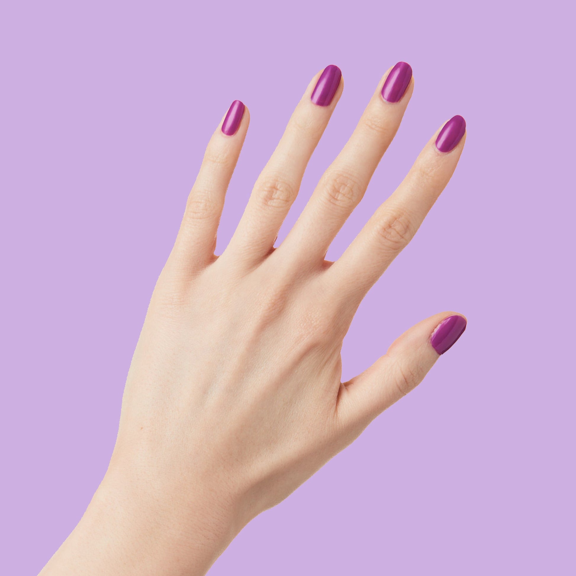 Hand with nails painted vibrant purple Grape Soda polish showing smooth, glossy manicure against lavender background