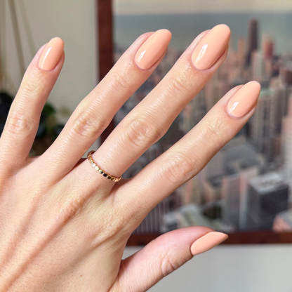 Hand with glossy nails coated in soft pastel melon shade It’s Serving Melon Cocktails for a fresh at-home manicure