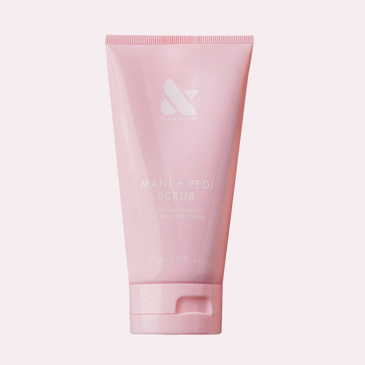 Pink tube of MANI + PEDI SCRUB with gentle exfoliating ingredients for soft, smooth hands and nails by Olive and June