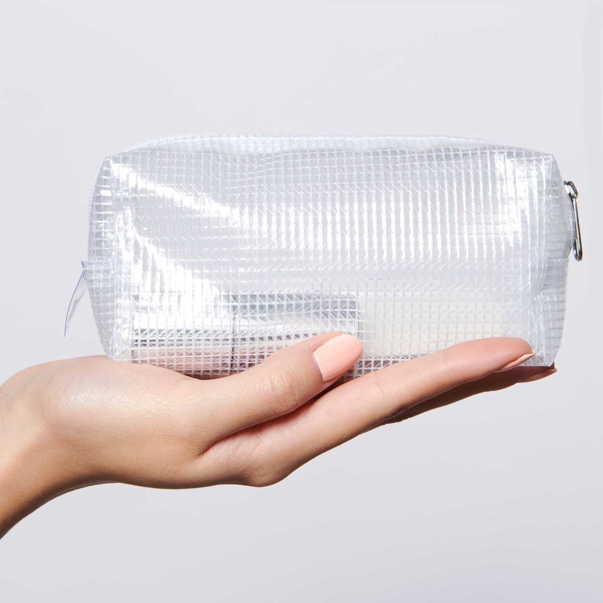 Hand holding The K.I.T. Kit clear pouch containing nail care essentials for mani and polish protection by Olive and June