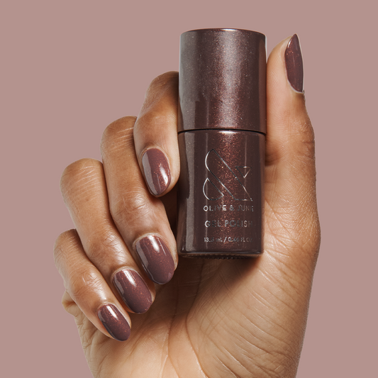 Hand with gel manicure in Goal Getter - Gel, a deep chocolate shade with golden shimmer, holding matching polish bottle