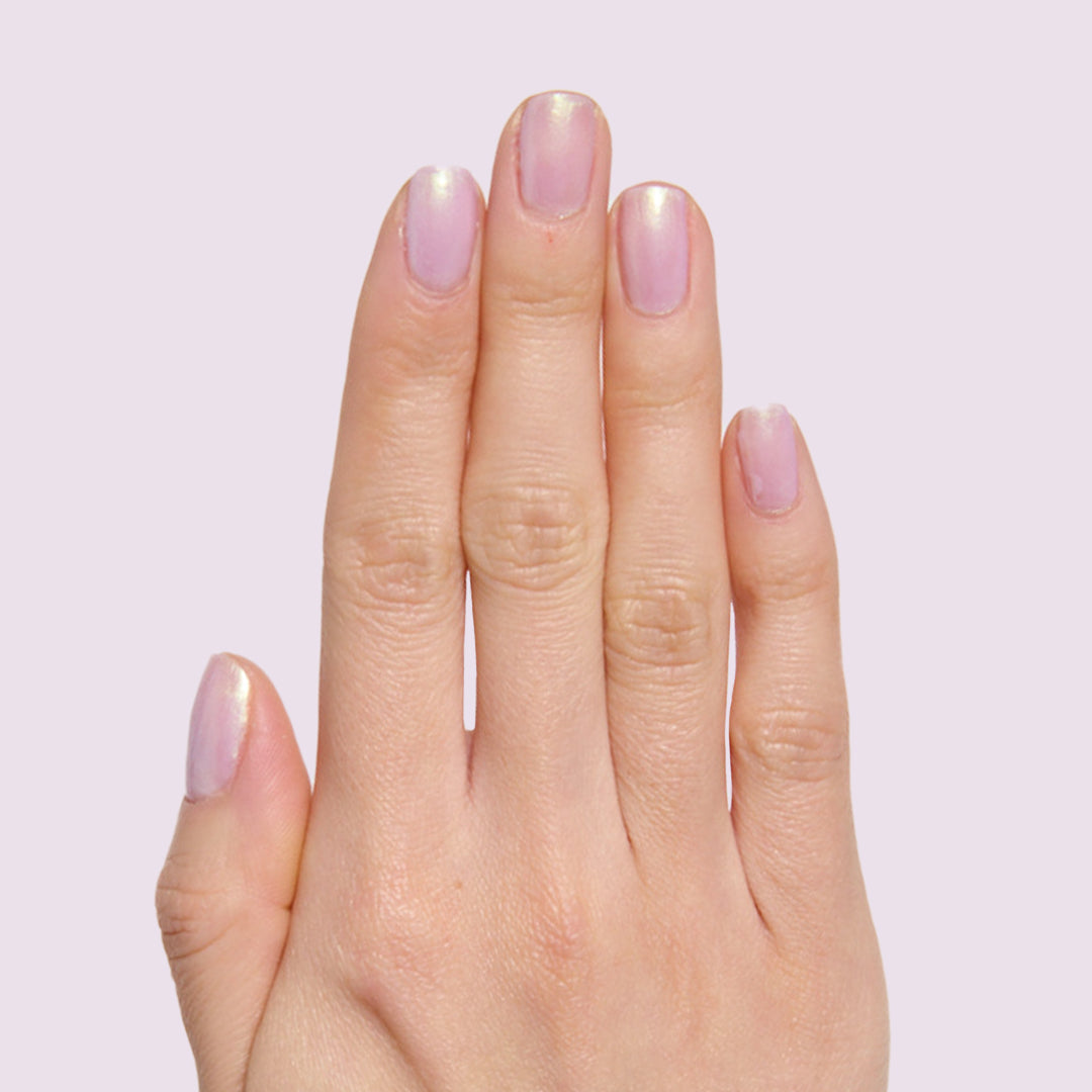 Hand with natural nails coated in sheer milky lavender Purple Puka polish showing a subtle iridescent finish manicure
