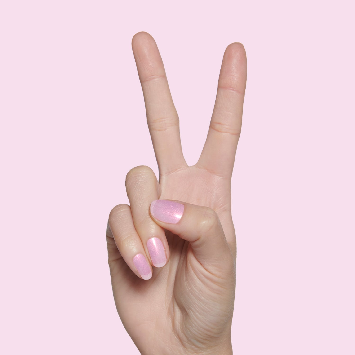 Hand showing two fingers with Pink Goldfish sheer pink iridescent polish for soft at-home manicure