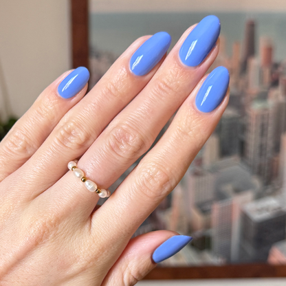 Hand with glossy nails painted in dusty ultramarine blue Rally Ready polish by Olive and June for a chic at-home manicure