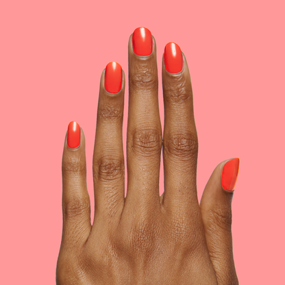 Hand showcasing a smooth, glossy Lava nail polish manicure in vibrant spicy orange-red on coral background
