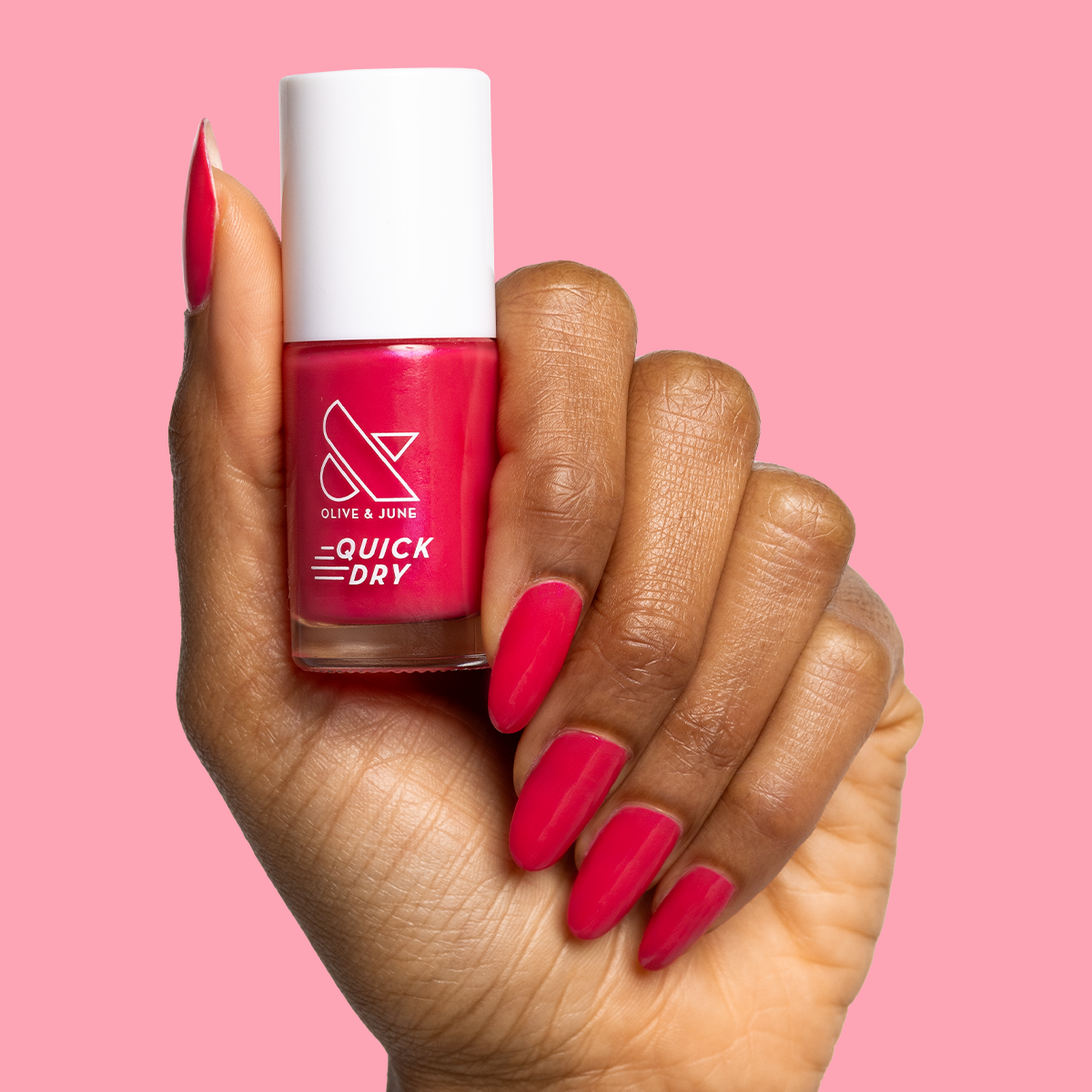 Hand holding Olive and June Berries quick dry polish with matching berry-pink gel mani against soft pink background