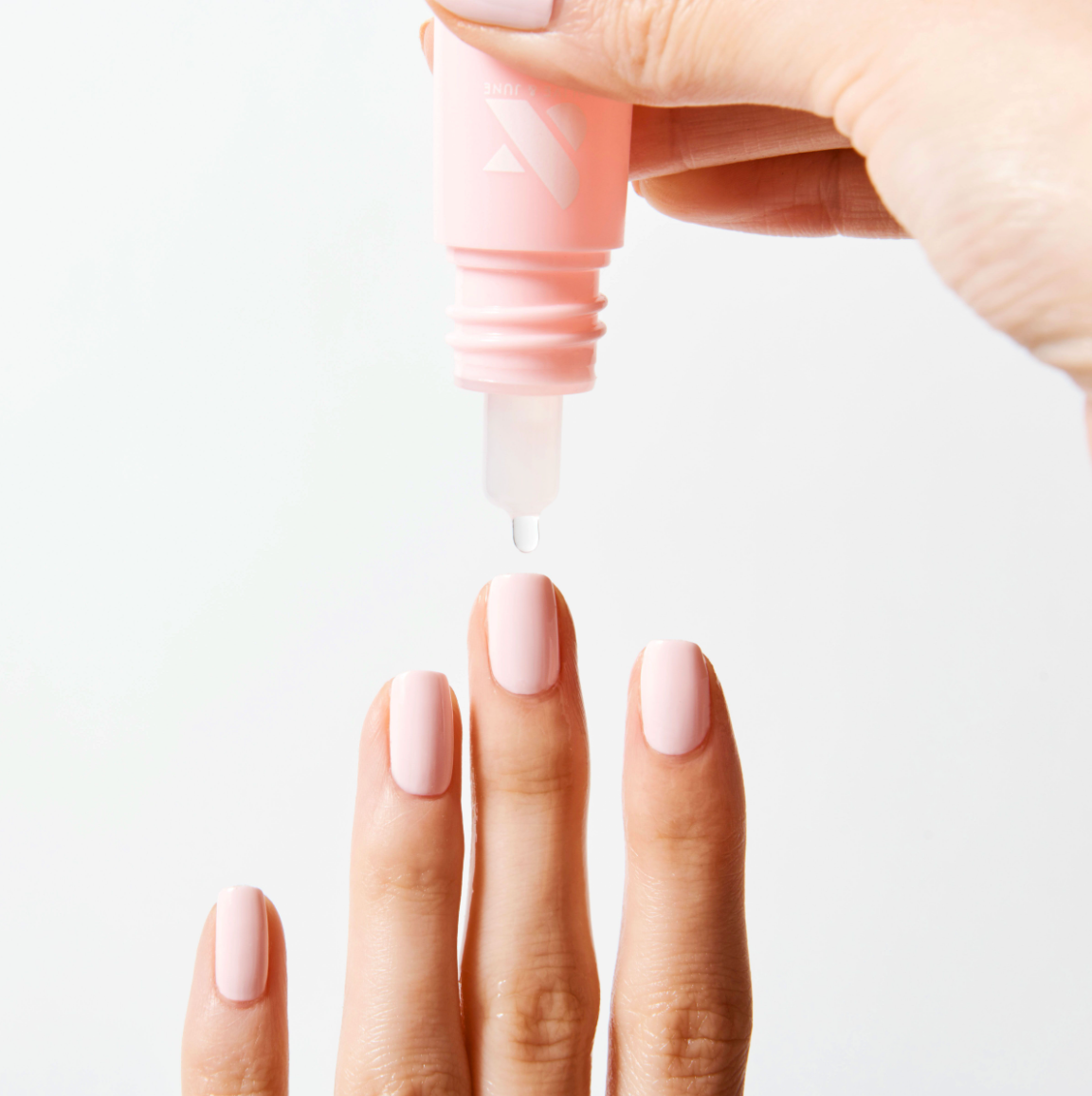 Drop from Dry Drops bottle about freshly manicured nails with soft pink polish for quick drying polish care