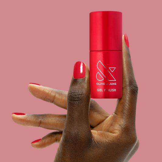 Secret Recipe - Gel bottle held by hand with glossy blue-toned red gel polish on nails for lasting manicure.