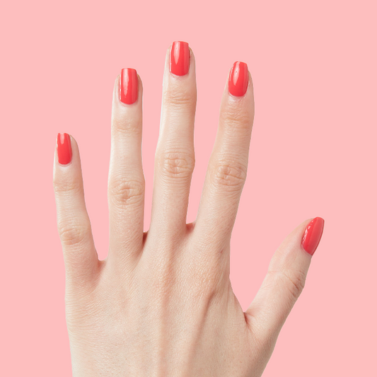 Hand with long nails painted in Field Day juicy watermelon red polish for a bright at home manicure look