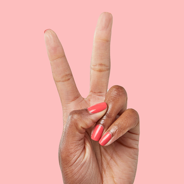 Hand showing peace sign with nails painted in Field Day juicy watermelon red quick dry polish for a bright mani